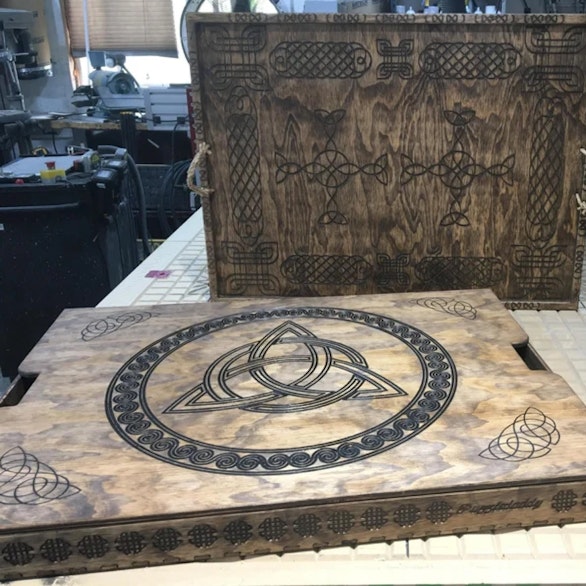 Wooden tray and its cover, both engraved with Celtic knotwork, in the workshop