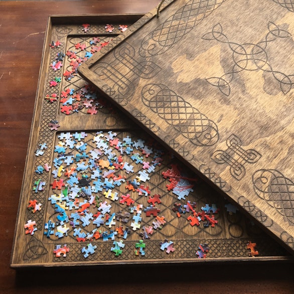 Wooden sorting tray with dividers holding unsorted jigsaw pieces, lid open